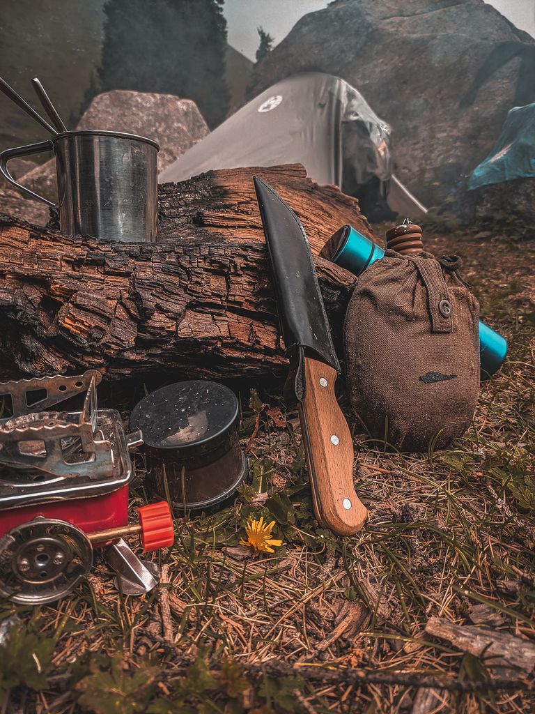Close-up of camping tools and equipment arranged near a tent.
